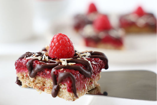 Eine No-Bake-Himbeer-Schnitte mit Schokoladentopping und einer frischen Himbeere