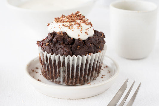 Schoko-Kirsch Muffin mit einem Löffel vegane Schlagcreme und geraspelter Dattel Schokolade