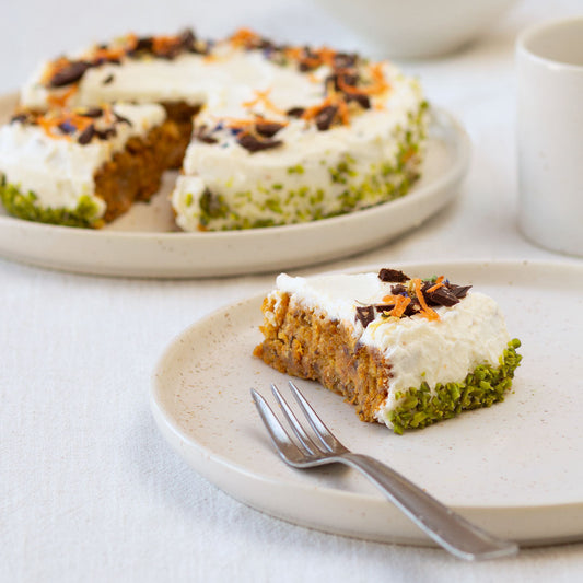 Kleiner Rüblikuchen mit veganem Frischkäse-Frosting und gehackter Schokolade, Pistazien und Karottenraspeln