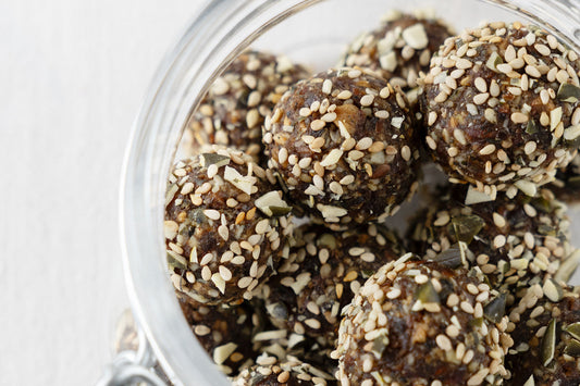 energy Balls mit Datteln, Kürbiskernen und Sesamsaat in einem wieder verschließbaren Glas