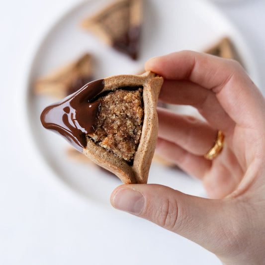 Veganes Schweizer Pfaffenhüetli mit einer Schokoladenecke aus MAKRi Dattel Schokolade. Gehalten zwischen zwei Fingern.