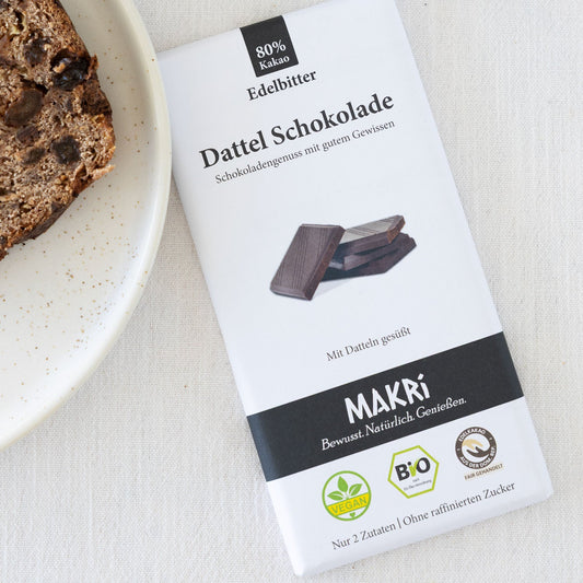 Eine Tafel Edelbitter-Schokolade neben einem Teller mit einer selbstgebackenen Leckerei