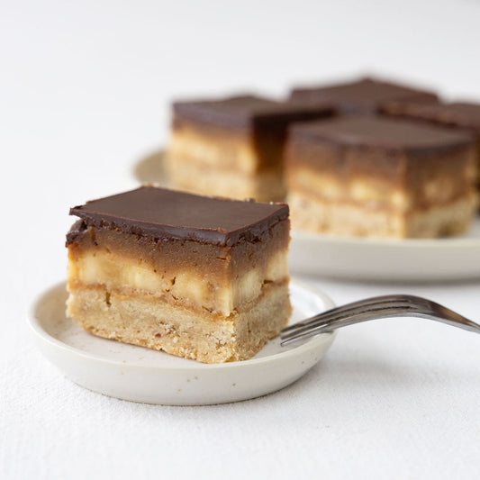 Veganes Banoffee mit Shortbread-Boden und Schokoladen-Topping verzehrfertig auf einem kleinen Teller angerichtet.