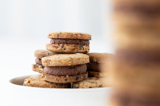 Vegane Walnuss-Schoko-Doppelkekse mit cremiger Füllung auf einem Teller gestapelt