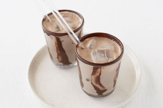 Zwei gläser Trinkschokolade mit Eiswürfeln und Trinkhalm